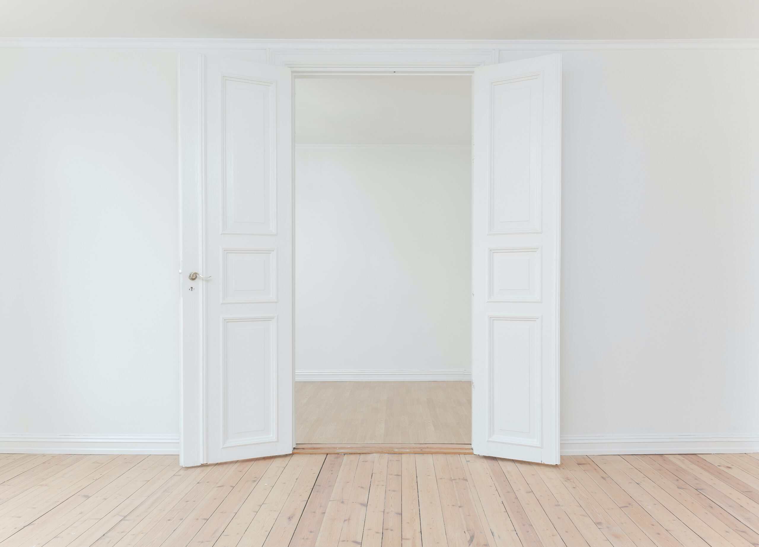 Portas de interior brancas abertas em uma parede branca minimalista.