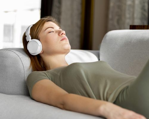 medium-shot-woman-couch-with-headphones